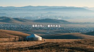 A white ger stands on a golden grassy hillside overlooking sprawling settlements and a distant city framed by mountains. Japanese text reads, “Beyond the grasslands, there is a city.”