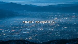山々に囲まれた京都南部の市街地と、都市を貫く光の交通軸。「古都の技は、世界の部品になった。」の文字