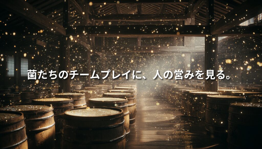 光が差し込む大きな蔵に木桶が並び、無数の粒子が舞う幻想的な発酵空間。中央に「菌たちのチームプレイに、人の営みを見る。」という白い文字が重なる。