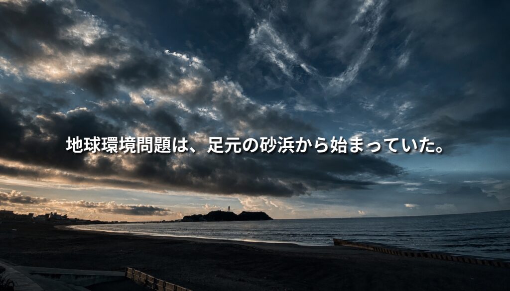 江の島を望む片瀬海岸の夕景。暗い雲と海岸線を背景に「地球環境問題は、足元の砂浜から始まっていた。」というコピーを重ねたアイキャッチ画像。