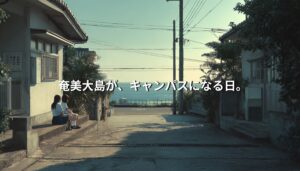 奄美大島の集落の道で、学生が静かに腰掛け、島の風景の中で過ごす様子。学びが日常に溶け込む滞在型キャンパスのイメージ。
