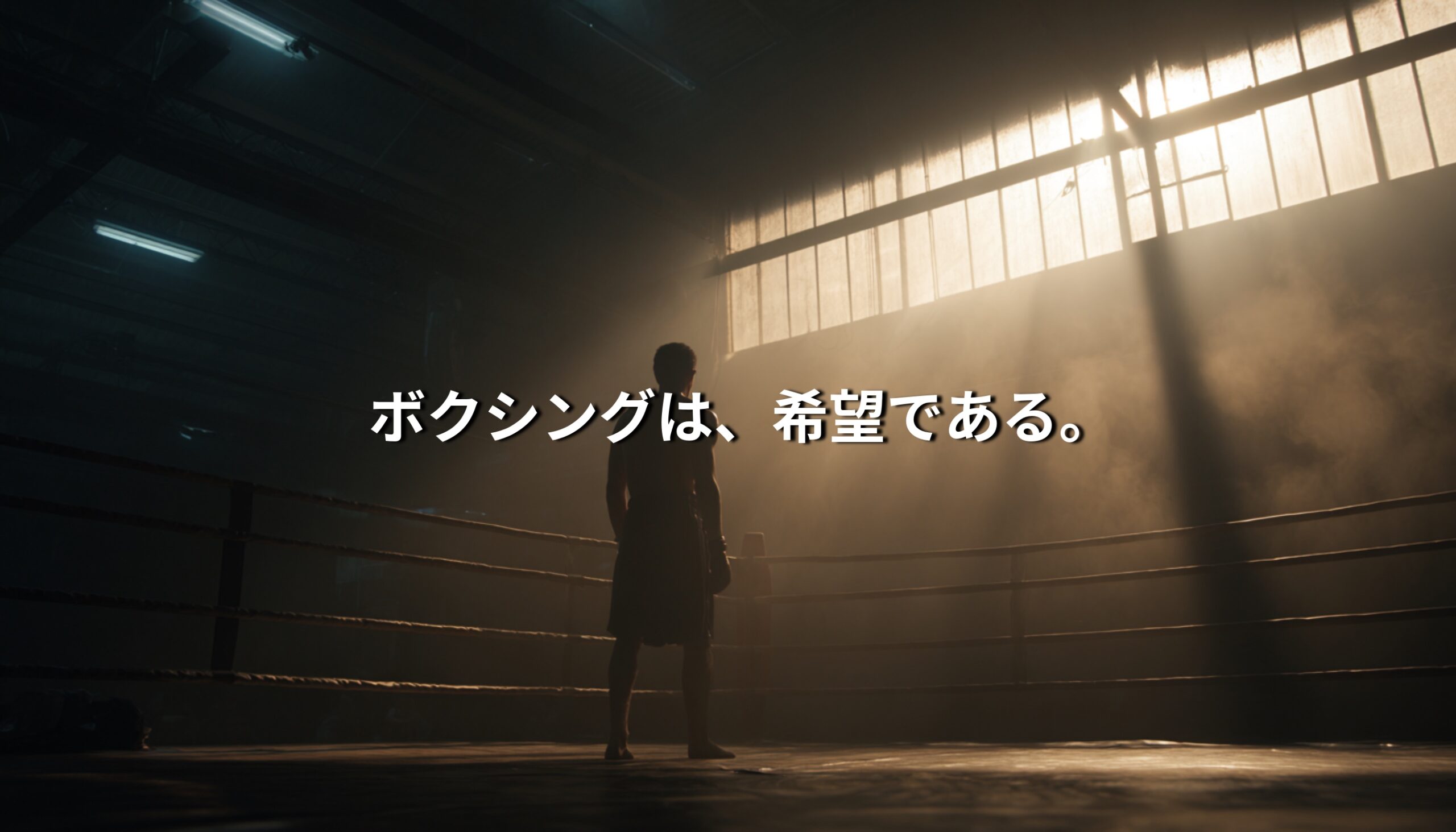 薄暗いジムのリングに立つボクサーのシルエット。窓から差し込む光の中に「ボクシングは、希望である。」という文字が重なる。