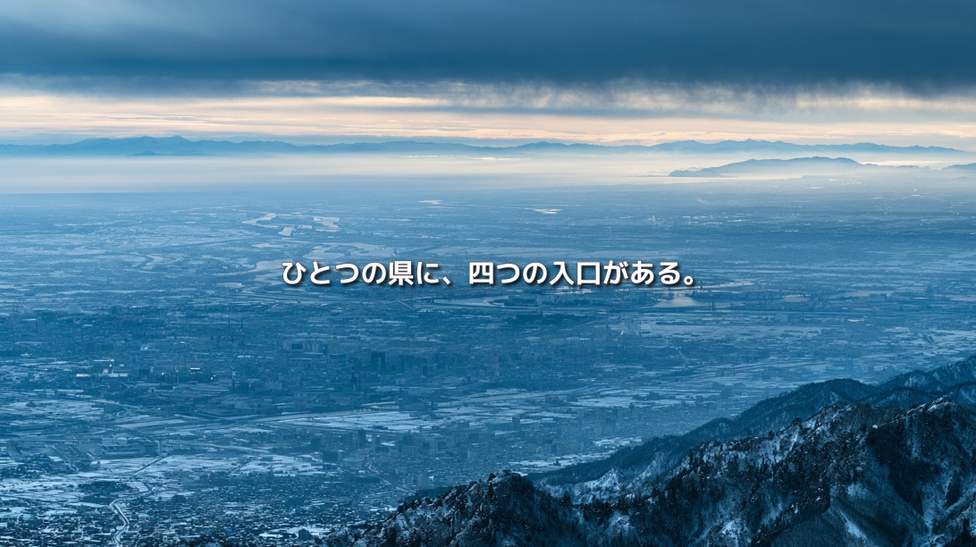 雪山から新潟の平野と市街地、日本海、佐渡を望む俯瞰風景。「ひとつの県に、四つの入口がある。」の文字